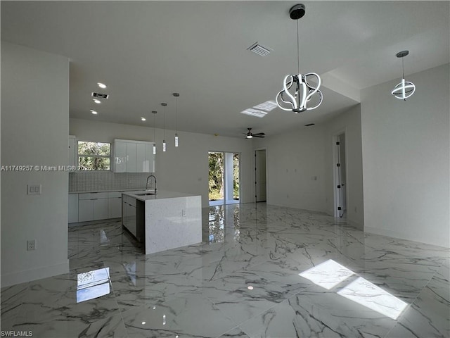 kitchen featuring light countertops, open floor plan, white cabinetry, and decorative light fixtures