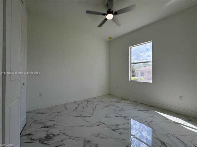 spare room with marble finish floor, baseboards, and a ceiling fan