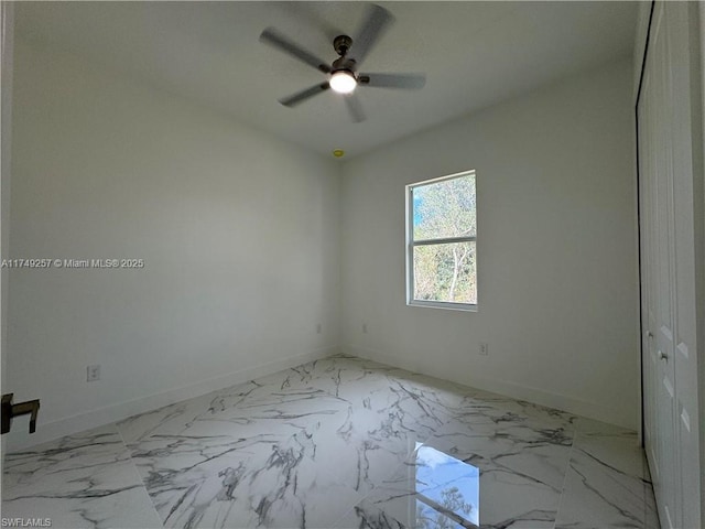 unfurnished room featuring marble finish floor, baseboards, and a ceiling fan