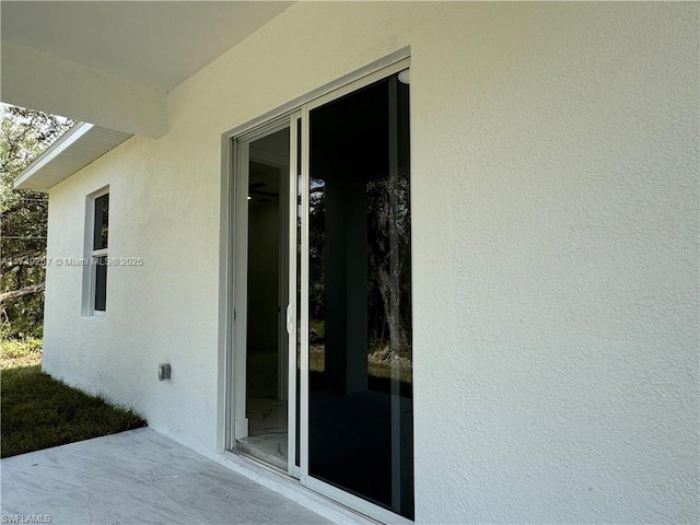 view of exterior entry featuring a patio and stucco siding