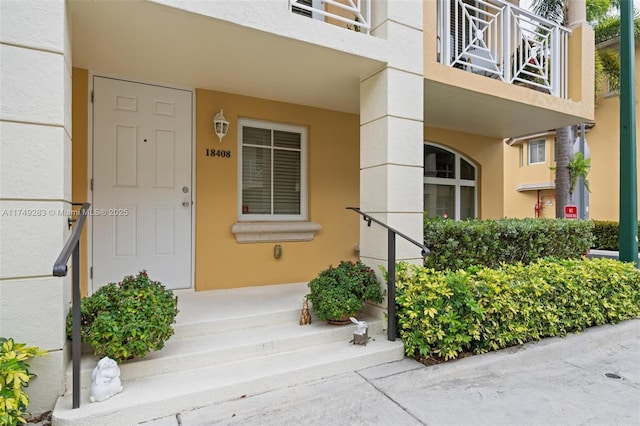doorway to property with stucco siding and a balcony