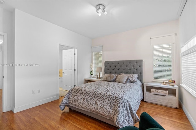 bedroom featuring baseboards, multiple windows, and light wood-style floors
