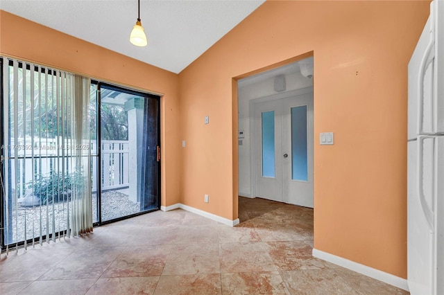 empty room featuring french doors, vaulted ceiling, and baseboards