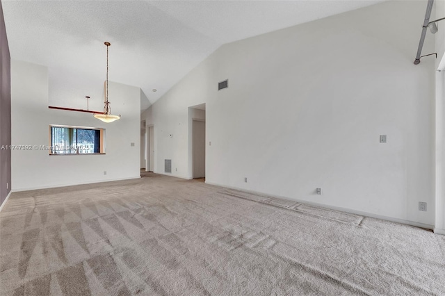 unfurnished living room with high vaulted ceiling, baseboards, visible vents, and light colored carpet