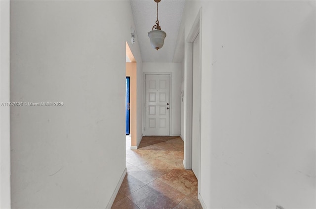 corridor with a textured ceiling and baseboards