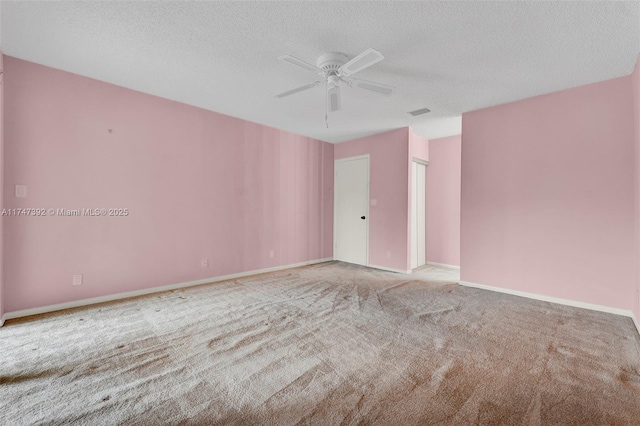 empty room featuring baseboards, a ceiling fan, a textured ceiling, and light colored carpet