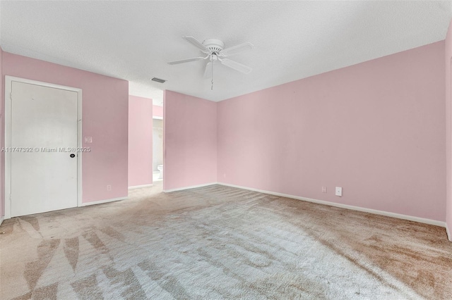 empty room with a textured ceiling, light carpet, visible vents, baseboards, and a ceiling fan