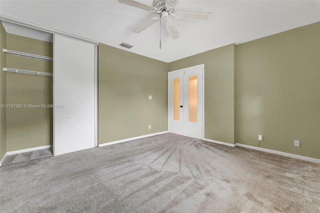 unfurnished bedroom with carpet floors, french doors, a closet, ceiling fan, and a textured ceiling