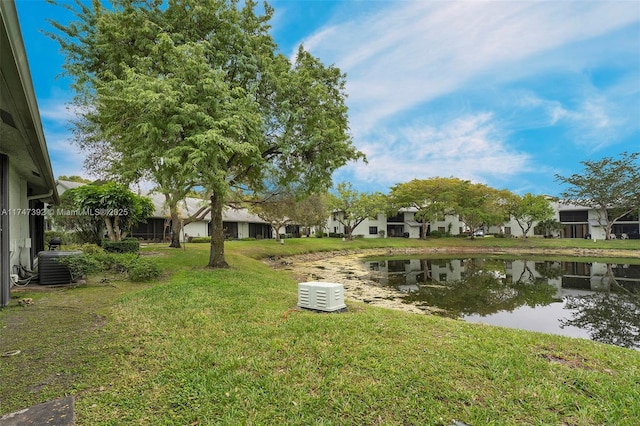 view of yard featuring a residential view, a water view, and central AC unit