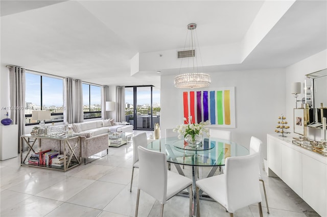 dining area featuring light tile patterned floors, visible vents, a wall of windows, and an inviting chandelier