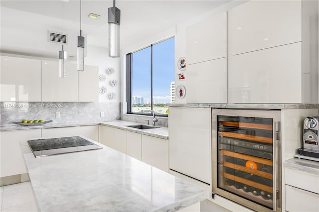 kitchen with wine cooler, white cabinets, decorative light fixtures, and modern cabinets