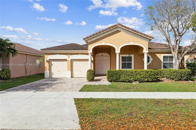 mediterranean / spanish-style house with a garage, a tiled roof, decorative driveway, and stucco siding