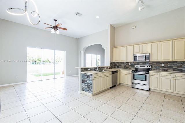 kitchen featuring visible vents, stainless steel appliances, cream cabinetry, and open floor plan