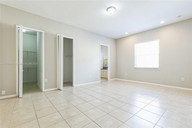 unfurnished bedroom with baseboards, a spacious closet, light tile patterned floors, and recessed lighting