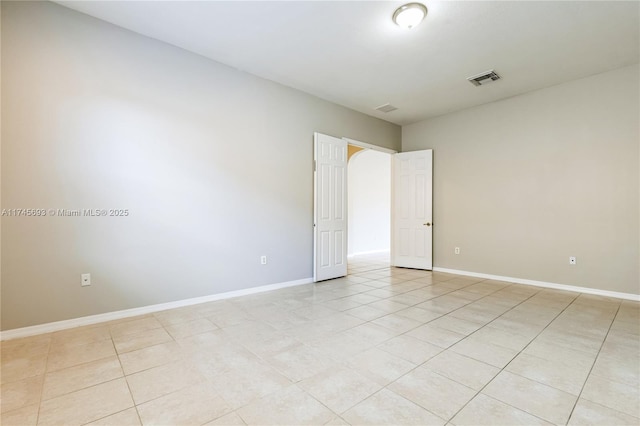 empty room with light tile patterned floors, visible vents, and baseboards