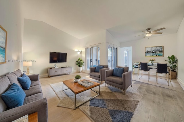 living area featuring high vaulted ceiling, light wood finished floors, a ceiling fan, and baseboards