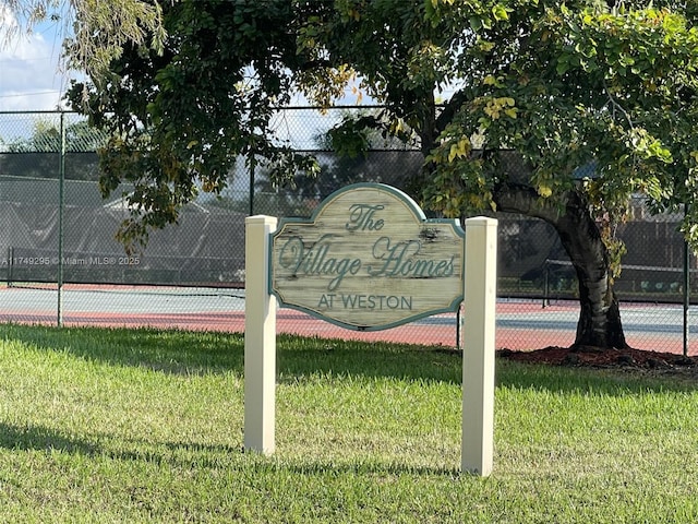 community sign featuring a lawn and fence