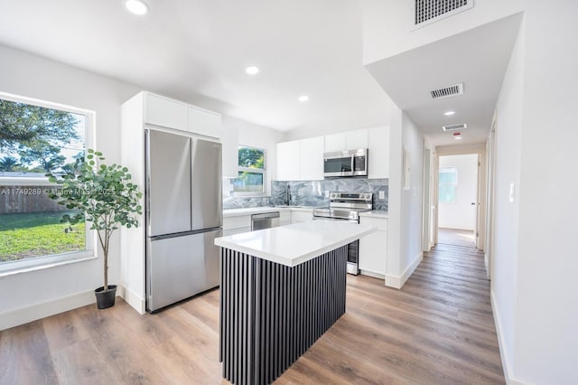 kitchen with a center island, tasteful backsplash, light countertops, appliances with stainless steel finishes, and white cabinetry