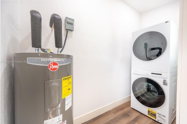 washroom featuring baseboards, water heater, dark wood finished floors, and stacked washing maching and dryer