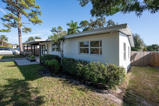 view of front of home featuring stucco siding, fence, a front lawn, and a patio