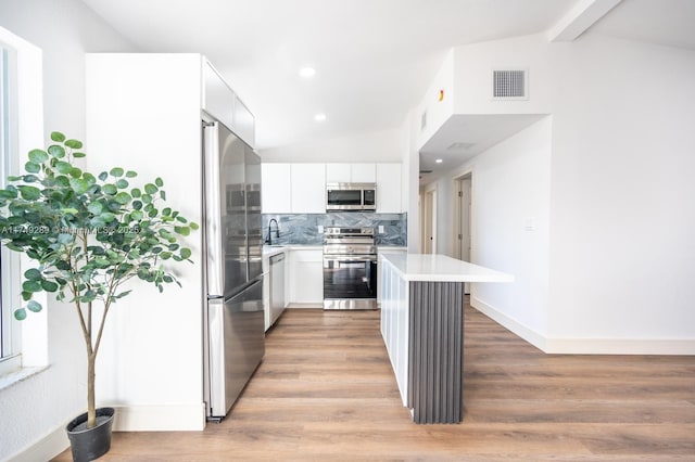 kitchen featuring visible vents, white cabinets, lofted ceiling with beams, stainless steel appliances, and light countertops