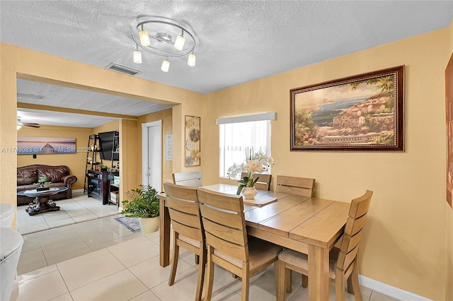 dining space with light tile patterned floors, a textured ceiling, visible vents, and baseboards