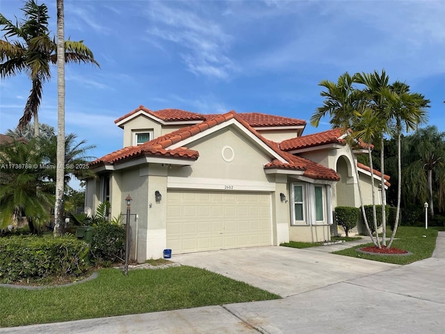 mediterranean / spanish-style home featuring stucco siding, a garage, concrete driveway, and a tiled roof