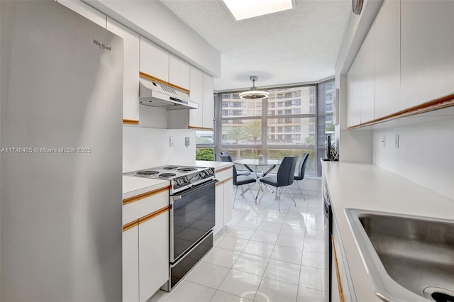 kitchen with light countertops, electric range oven, freestanding refrigerator, white cabinetry, and under cabinet range hood