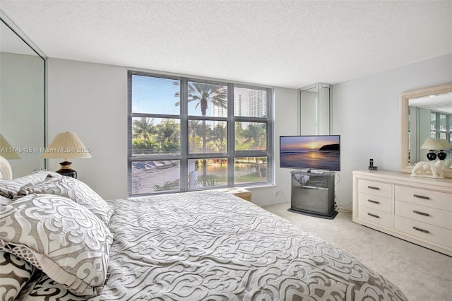 bedroom featuring light carpet and a textured ceiling
