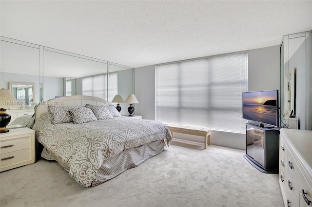 bedroom with light colored carpet and a textured ceiling