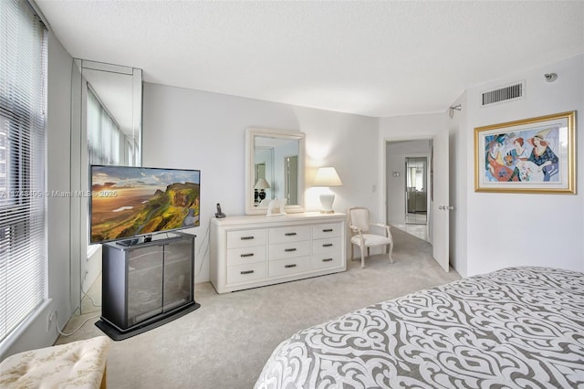 bedroom featuring visible vents, a textured ceiling, and light colored carpet