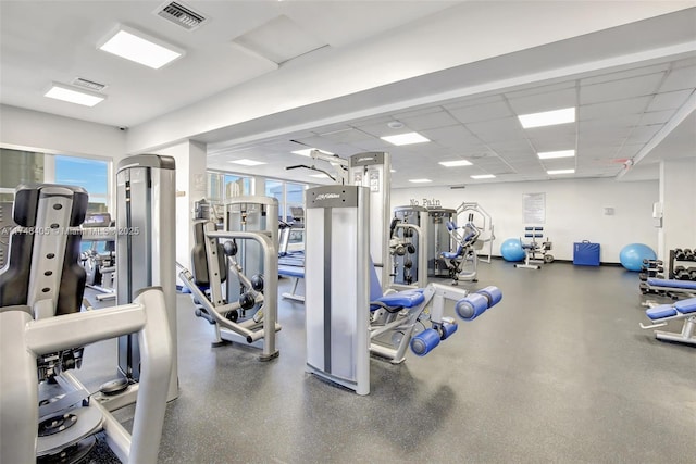workout area with a drop ceiling, visible vents, and baseboards
