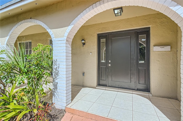 entrance to property featuring brick siding and stucco siding