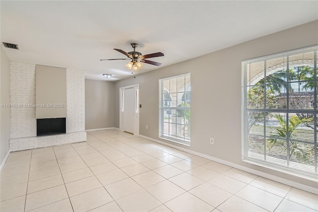 unfurnished living room featuring a ceiling fan, a brick fireplace, visible vents, and light tile patterned flooring