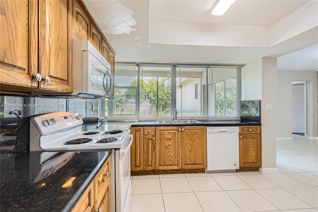 kitchen with white appliances, brown cabinetry, a sink, and light tile patterned flooring