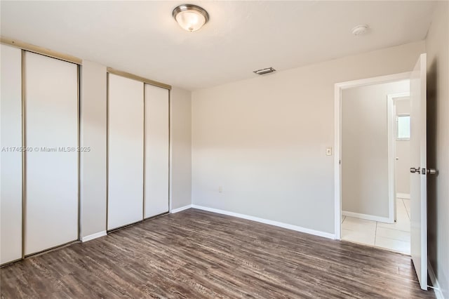 unfurnished bedroom with multiple closets, baseboards, and wood finished floors