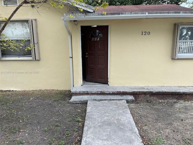 property entrance with roof with shingles and stucco siding