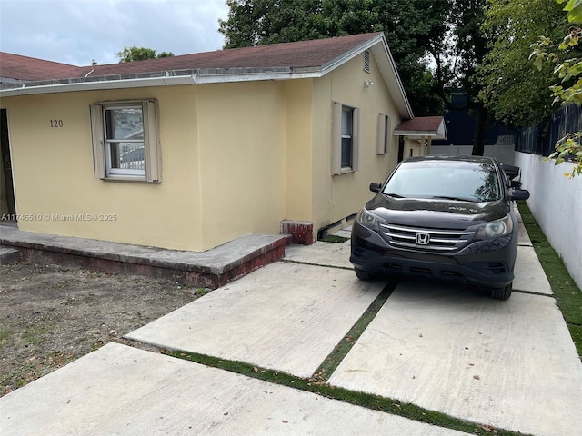 120 NE 75th St, Miami, FL 33138 - view of side of property with stucco siding, a shingled roof, and a patio