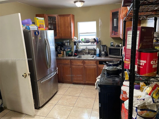 120 NE 75th St, Miami, FL 33138 - kitchen featuring light tile patterned floors, dark countertops, glass insert cabinets, stainless steel appliances, and a sink