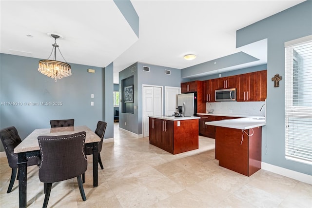 kitchen featuring a center island, decorative light fixtures, stainless steel appliances, light countertops, and baseboards