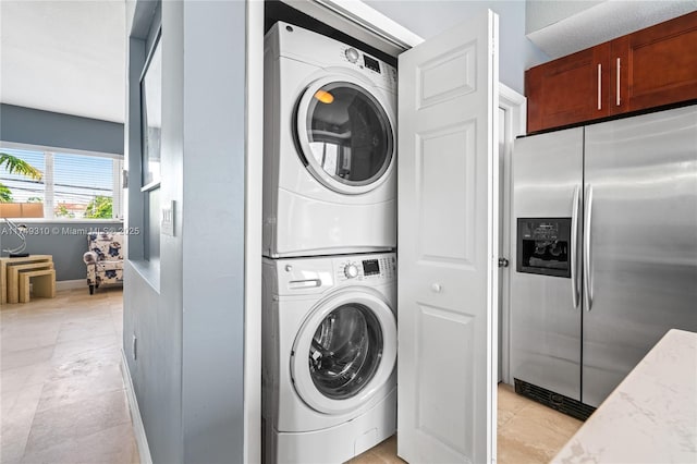 laundry room featuring laundry area, stacked washer / dryer, and baseboards