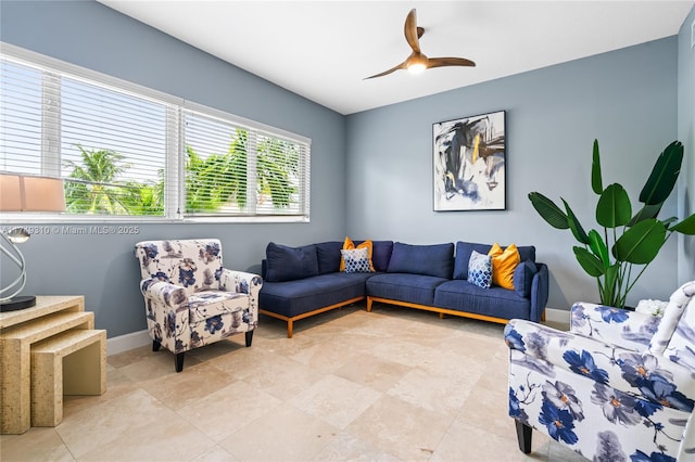 living area featuring a ceiling fan and baseboards