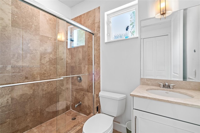 bathroom with a closet, vanity, toilet, and a stall shower