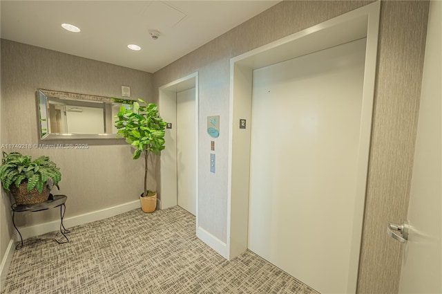 hall featuring elevator, baseboards, wallpapered walls, and recessed lighting