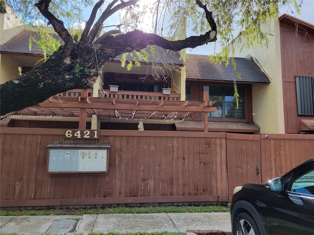 exterior space with a shingled roof, fence, and stucco siding