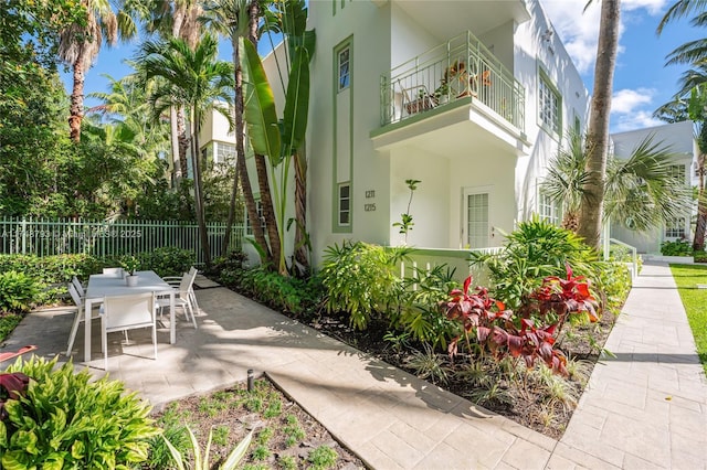 view of patio featuring outdoor dining space, fence, and a balcony