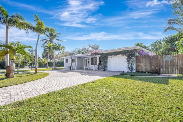 single story home with a front lawn, decorative driveway, fence, and an attached garage