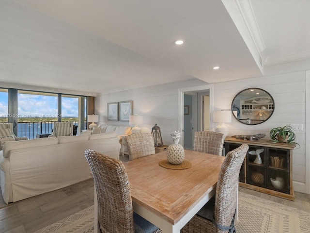 dining room featuring light wood finished floors, a water view, recessed lighting, and crown molding