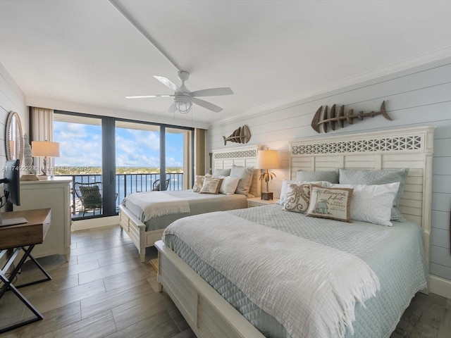 bedroom featuring a water view, wood finished floors, a ceiling fan, and access to exterior