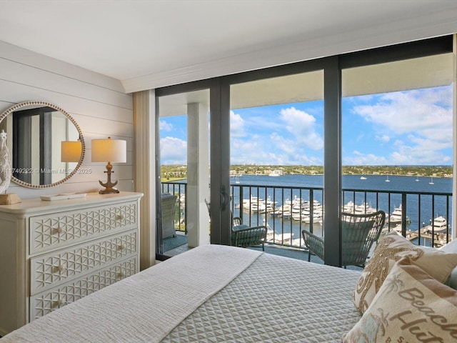 bedroom with access to exterior, floor to ceiling windows, a water view, and wooden walls